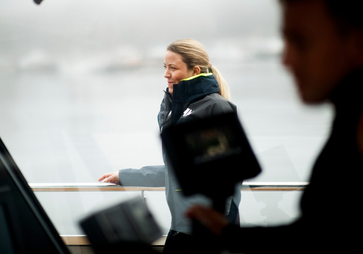 En kvinne som går på dekk på en båt, sett gjennom vinduet på broen. Foto.