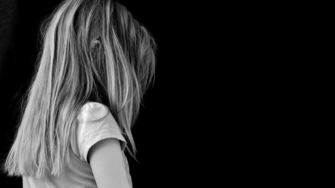 Sort-hvitt-bilde av en uidentifiserbar jente mot en sort bakgrunn. 