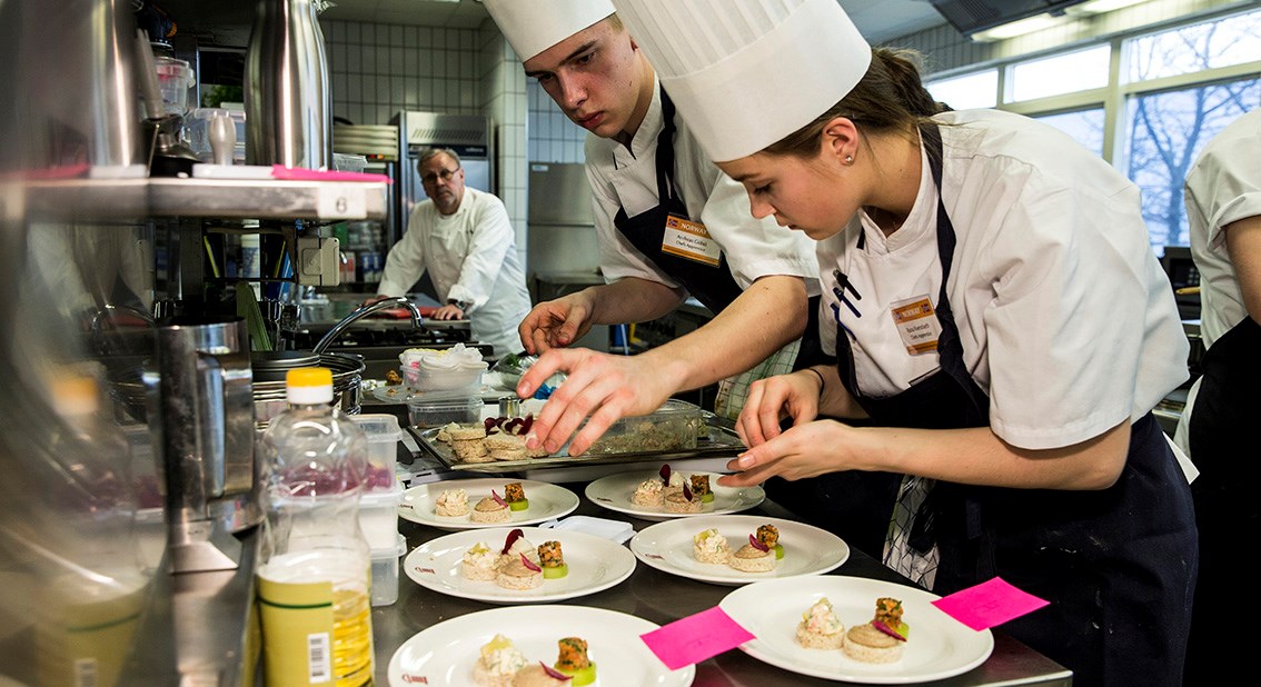 Bilde av Kokkelærlingene Andreas Gøbel og Runa Kvendseth gjør klar kanapeer til servering. 