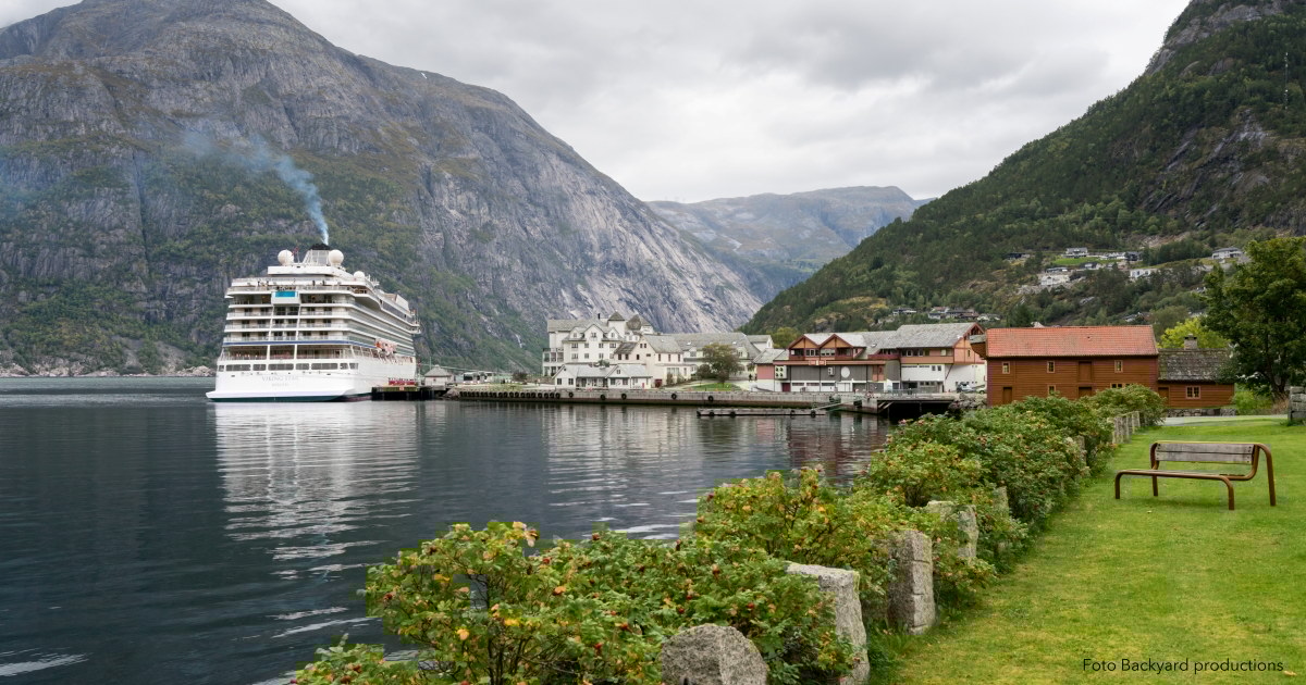 Et cruiseskip som ligger til havn i en fjord.