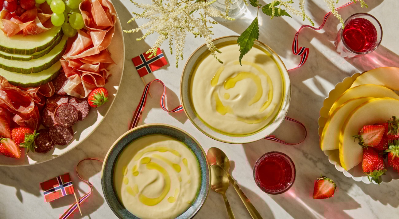 Rømmegrøt på bord med norske flagg, spekemat og flagg. Foto.