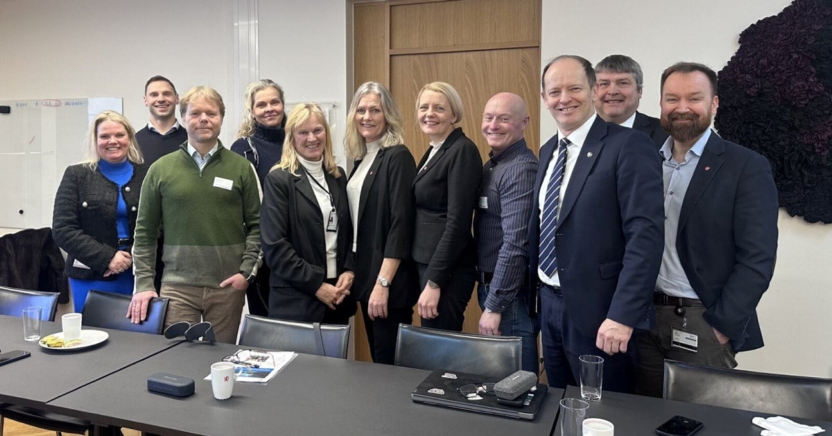 En gruppe mennesker som står samlet bak et bord i et møterom.
