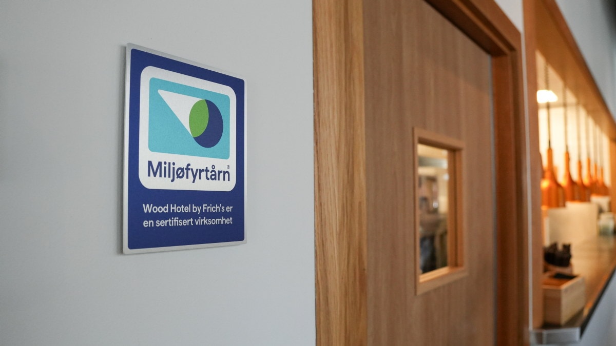 Miljøfyrtårn-skilt på en vegg ved siden av en tredør.