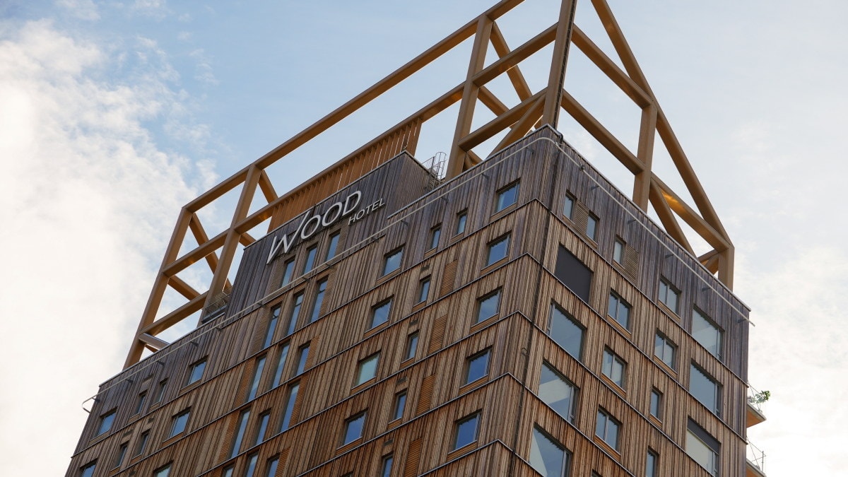 Utsnitt av Wood Hotel sett nedenfra, med trefasade, vinduer og hotellskilt øverst på bygget.