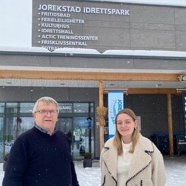 To personer står utenfor Jorekstad idrettspark på Lillehammer i vinterlandskap