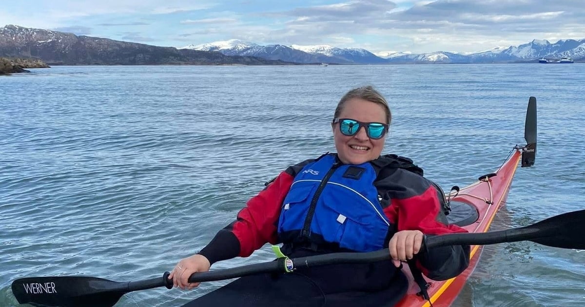 Glad kvinne med solbriller i kajakk ute på havet