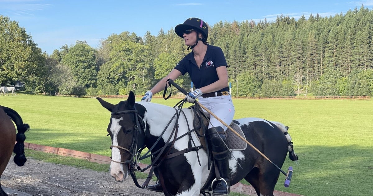 Kvinne til hest som spiller polo i grønne omgivelser