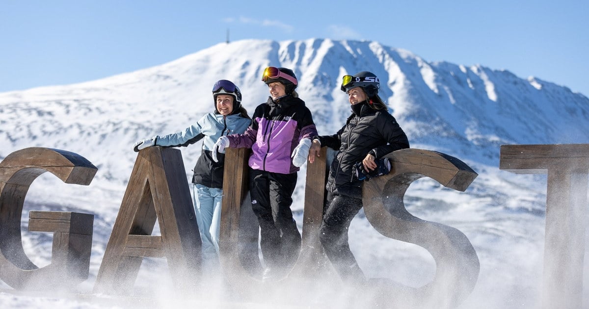 Tre personer i skiutstyr står ved bokstavene i Gausta-skiltet i snøen med fjell bak. Foto