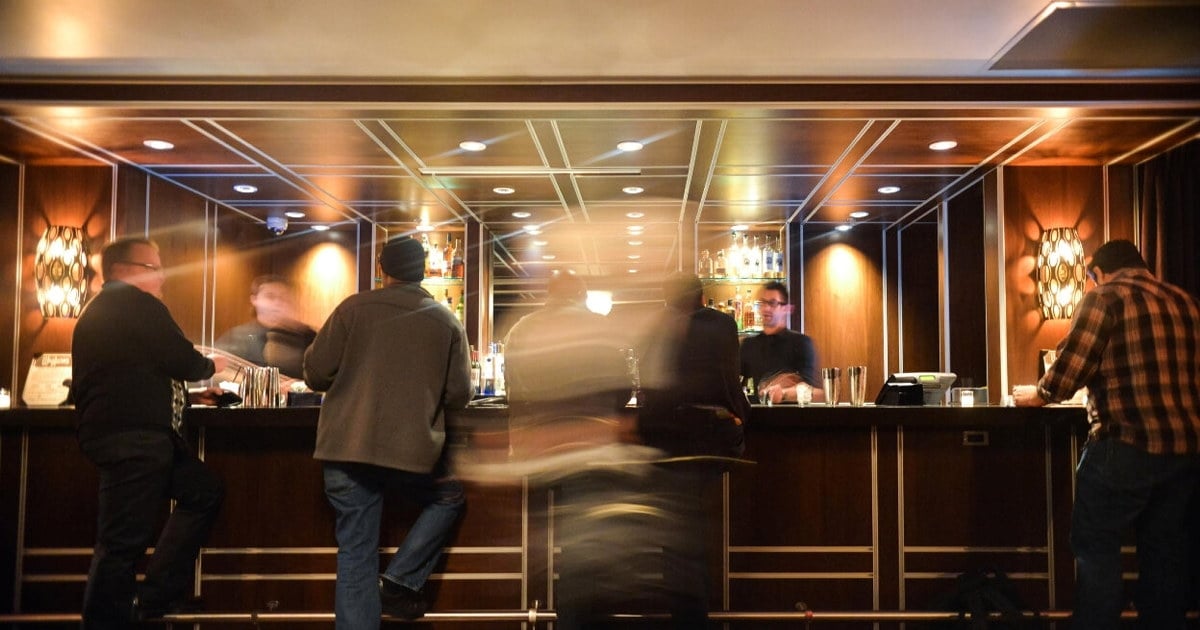 Bilde fra en hotellbar tatt med lang utløsertid, slik at menneskene fremstår uklare. Foto.