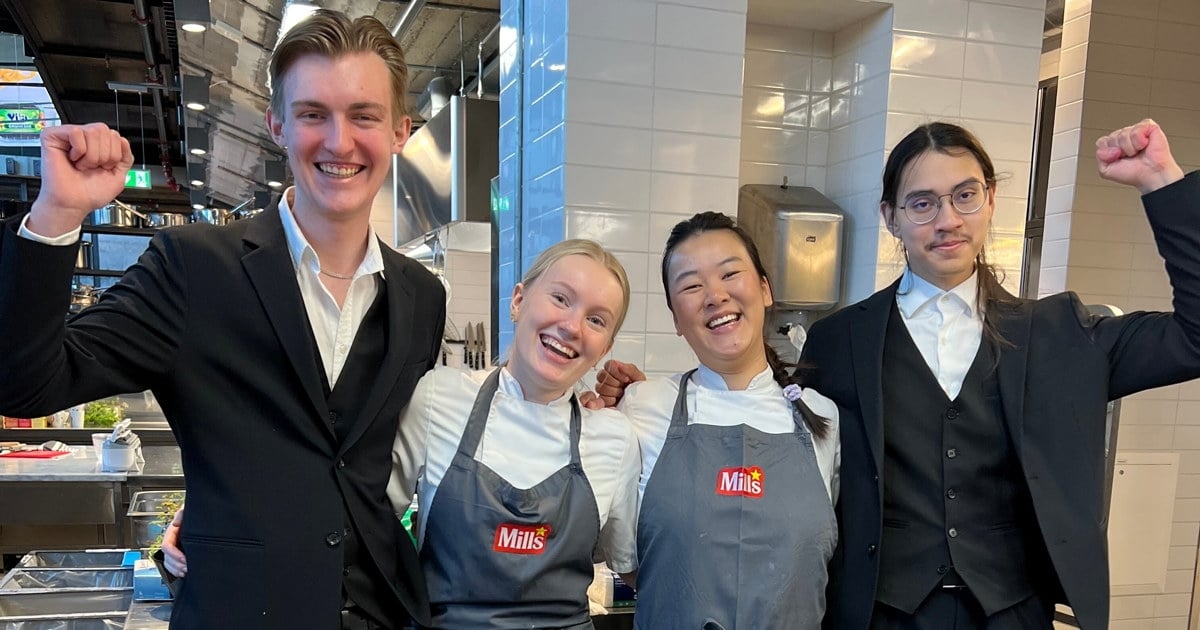 Lagbilde av to kokker og to servitører som står på et restaurantkjøkken.