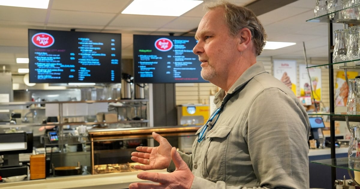 En person står ved disken i en kafé og snakker.