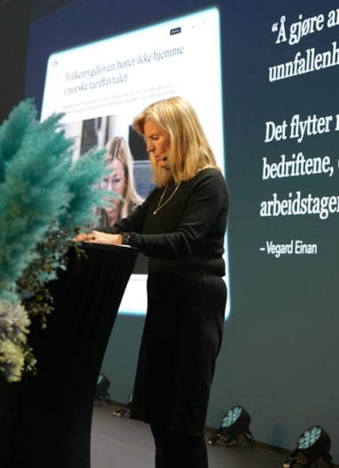 En person står på en scene og holder et foredrag.