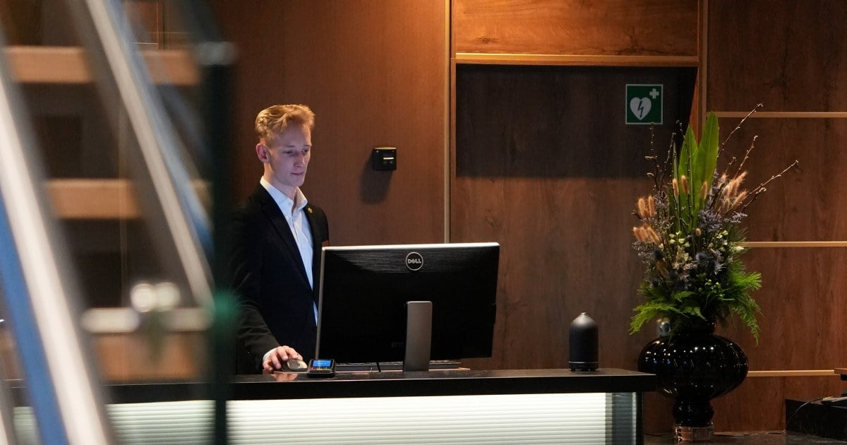 Ansatt bak en resepsjonsdisk, fotografert gjennom trappekonstruksjonen i lobbyen.