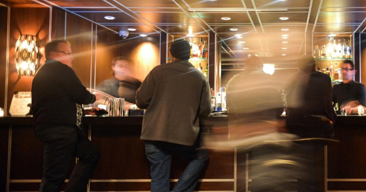 Bilde fra en hotellbar tatt med lang utløsertid, slik at menneskene fremstår uklare. Foto.