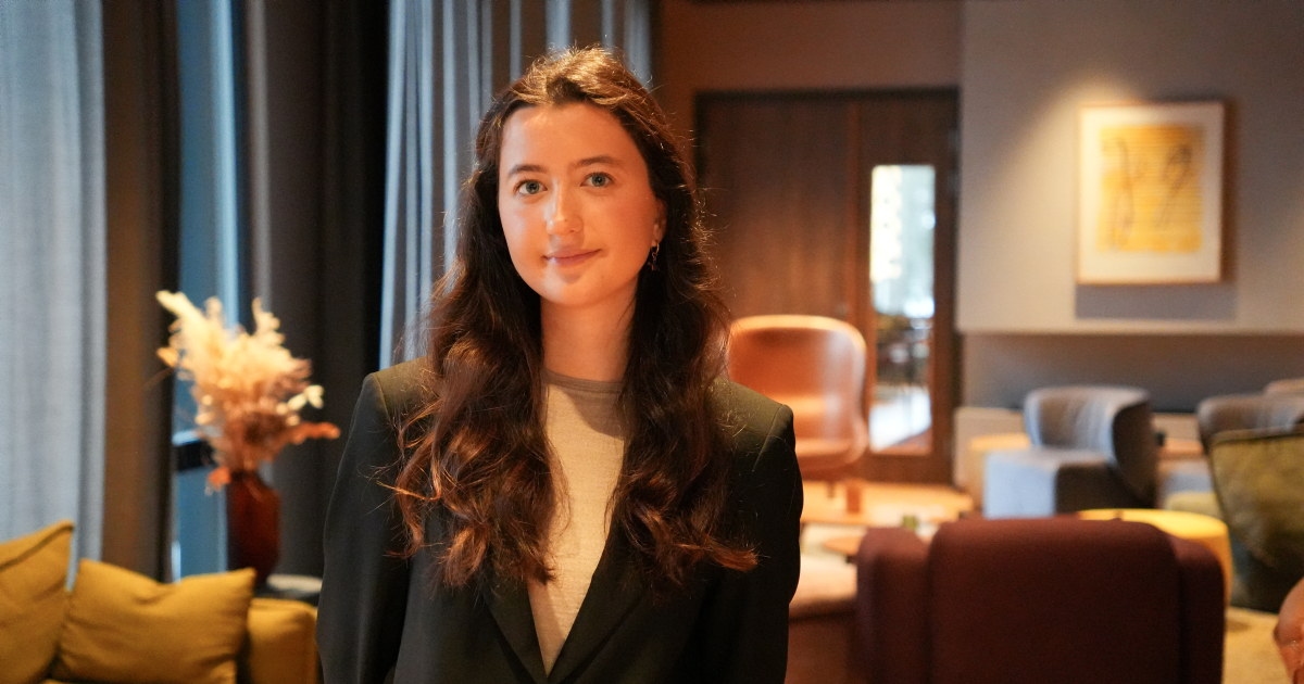 Portrett av en hotellansatt i et loungeområde med sofaer og lenestoler.