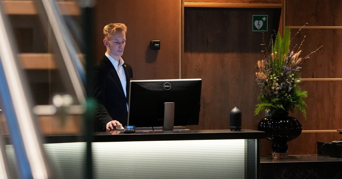 Ansatt bak en resepsjonsdisk, fotografert gjennom trappekonstruksjonen i lobbyen.