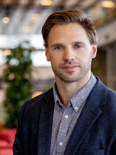 Portrett av sittende mann som ser inn i kamera. Foto.