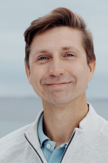 Potrettfoto av en mann med blå piqué-skjorte og lys jakke.