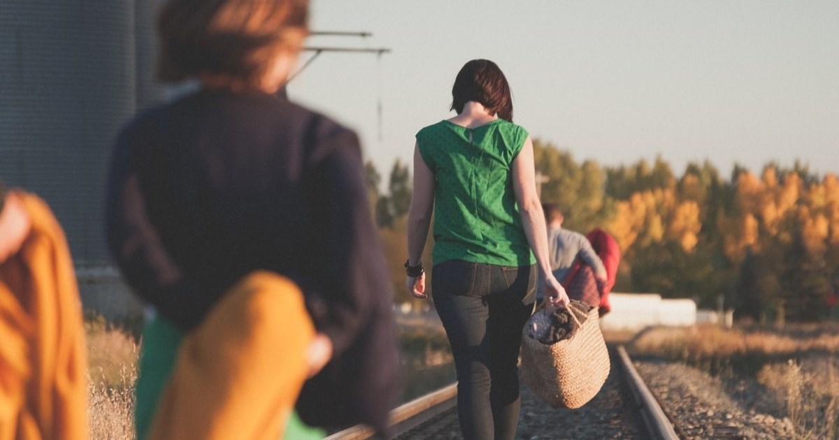 Illustrasjonsbilde av en kø av mennesker som går langs et jernbanespor, bærende på eiendeler. Foto.