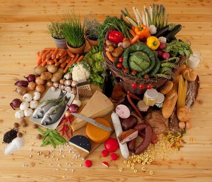 Matvarer, grønnsaker, oster og fisk spredt utover et bord. Foto.