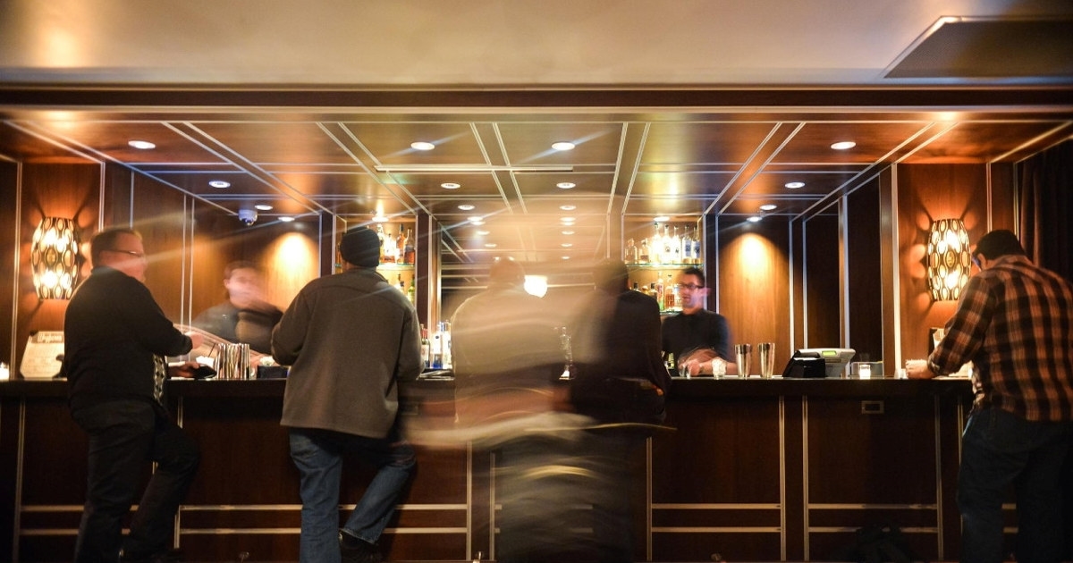 Bilde fra en hotellbar tatt med lang utløsertid, slik at menneskene fremstår uklare. Foto.