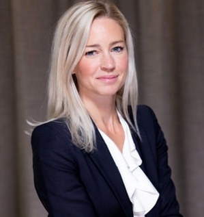 En smilende kvinne iført dressjakke og hvit bluse. Portrettfoto.