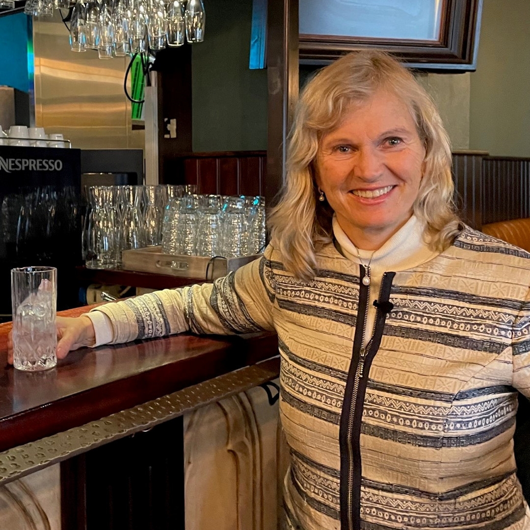 Bilde av en smilende kvinne i en bar. Foto