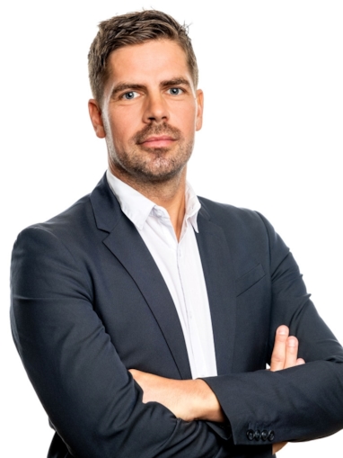 Mann med armene i kryss som ser inn i kamera. Foto