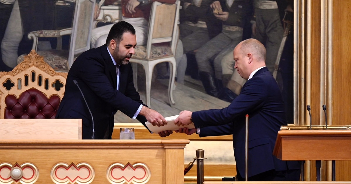 En mann som overrekker et tykt dokument til en annen. Foto