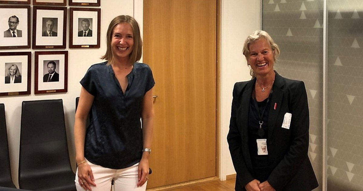 To smilende kvinner stående inne på et kontor. Foto.