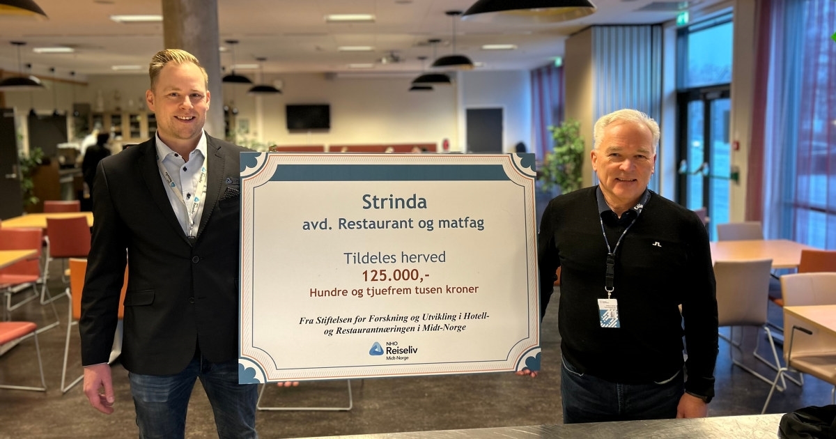 2 mennesker blir tatt bilde av, hvor de har holder en plakat hvor det fremkommer en pengesum som blir delt ut til Strinda vgs. avdeling Restaurant- og matfag