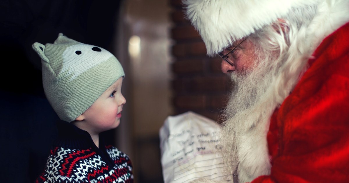 En liten gutt sammen med julenissen. Foto.