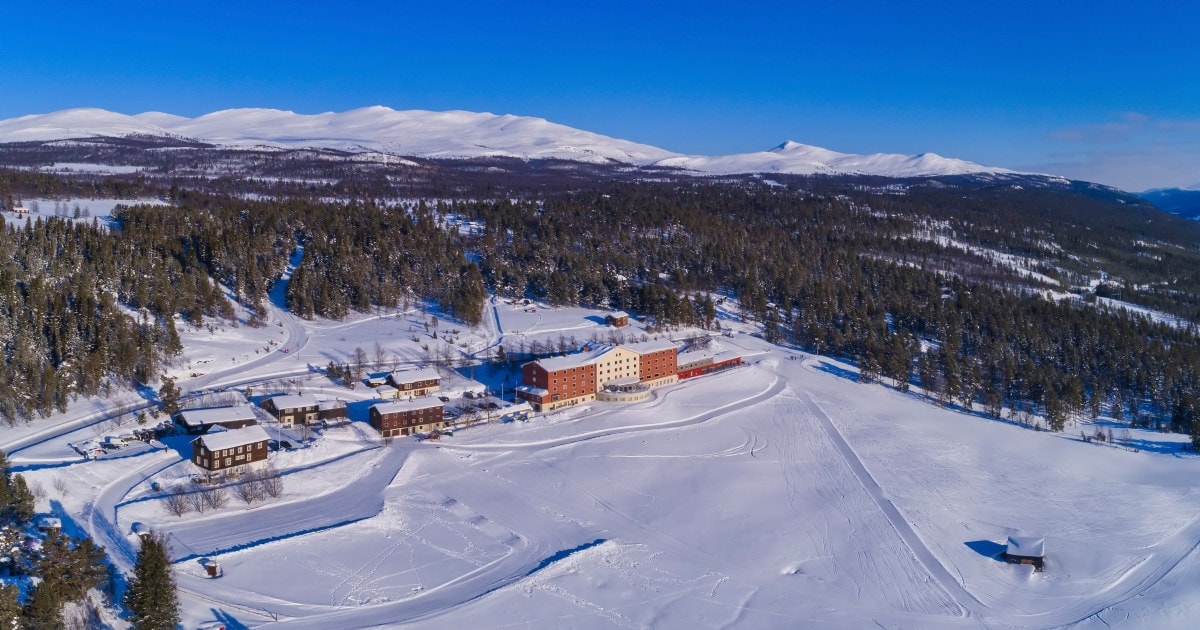 Et naturbilde av et stort hotell. men snø rundt og blå himmel