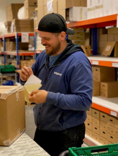 Ansatt i Norganic som holder en pakke på et lager.