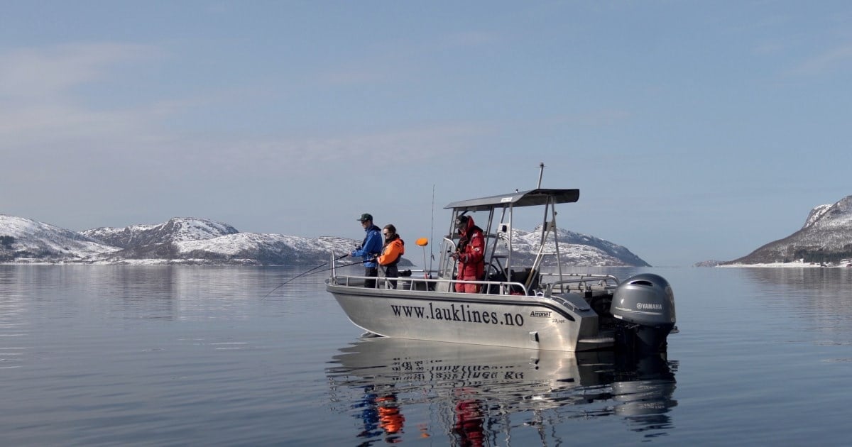 En motorbåt med fiskere om bord, på stille hav. Foto