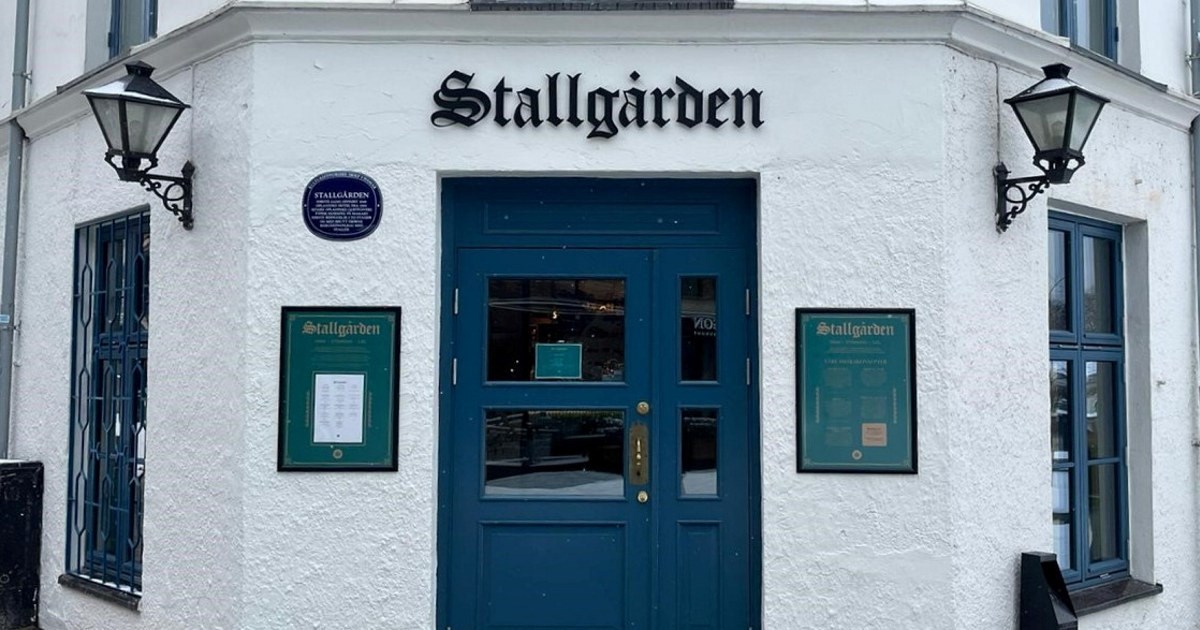 Hvitt bygg med blå dør, med "Stallgården" skilt over inngangen.