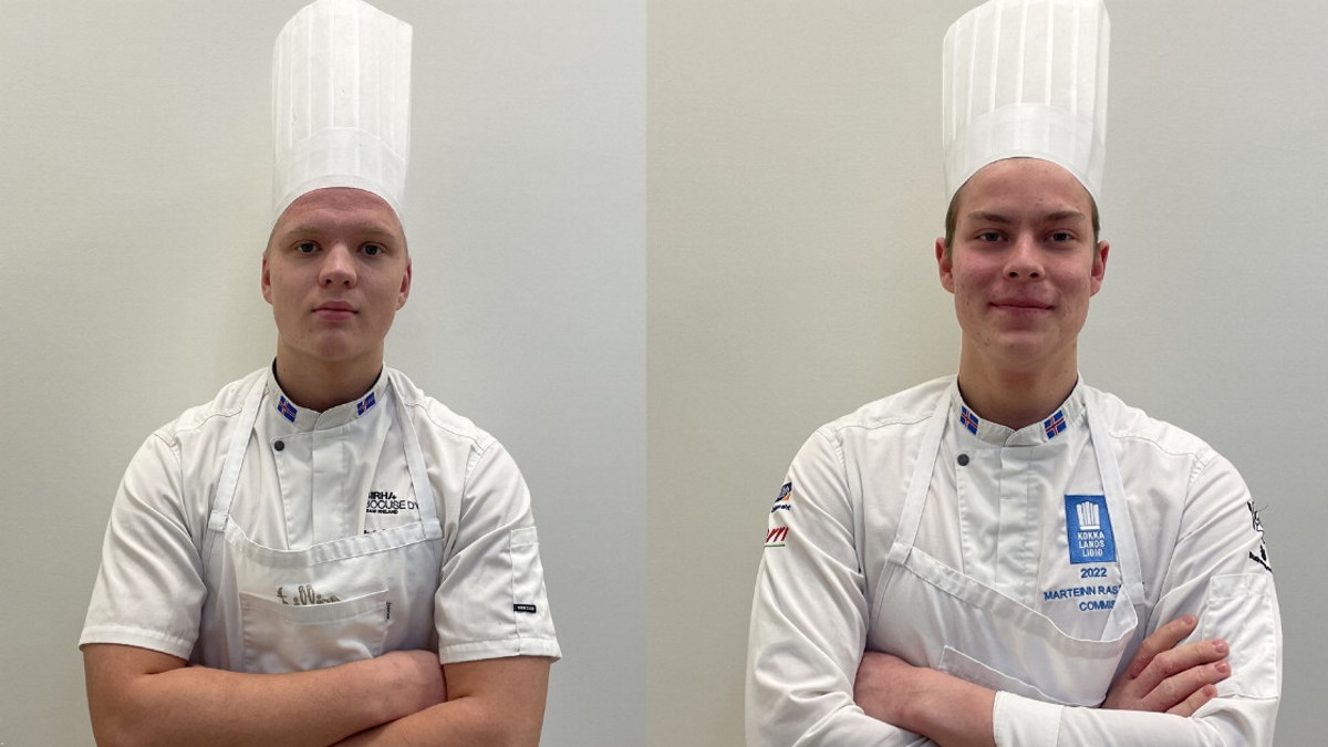 To unge menn i kokkeklær og kokkehatter. Foto