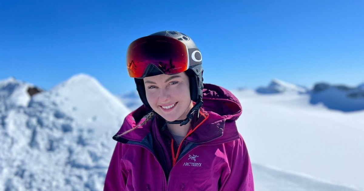 Marthe på en fjelltopp smilende mot solen. Skihjelm og skibriller på hodet. Rosa jakke.