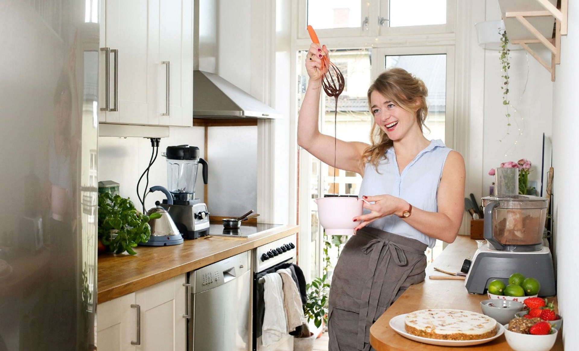 en kvinne som holder en visp over en bakebolle på et hjemmekjøkken. Foto