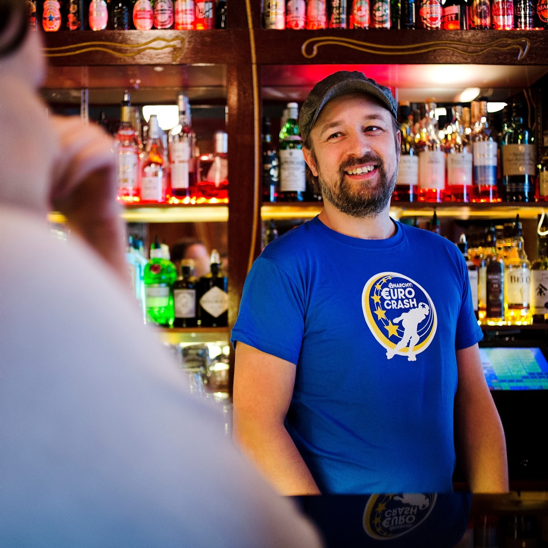 Smilende bartender bak bardisken. Foto.