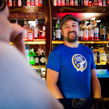 Smilende bartender bak bardisken. Foto.