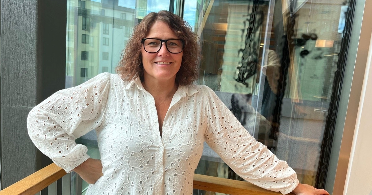 Mette Rokseth. Hvit kjole og krøllete brunt hår. Briller. Foto.