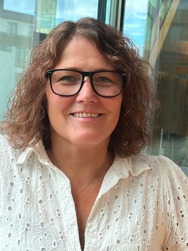 Mette Rokseth. Hvit kjole og krøllete brunt hår. Briller. Foto.