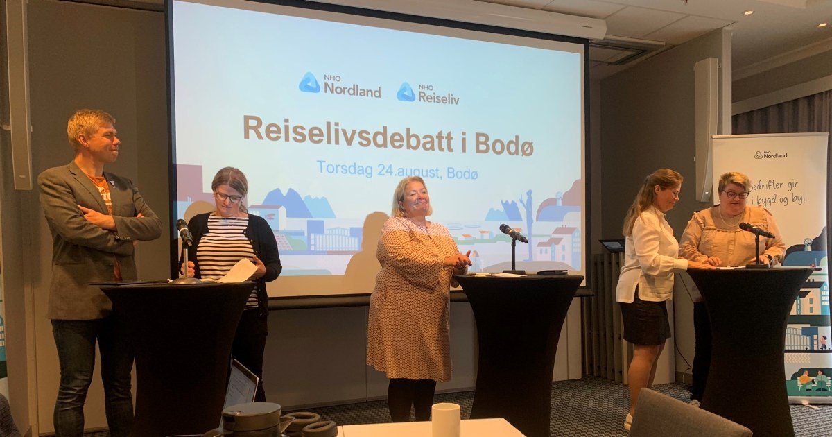 fem personer son står på en scene foran en presentasjon som viser teksten "Reiselivsdebatt i Bodø". Foto.