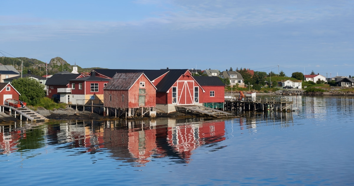 Røde hus ved vannkanten. Foto.