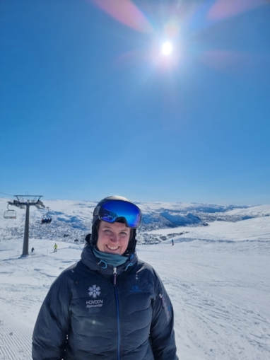 Kvinne i skiutstyr i skibakken som ser i kamera
