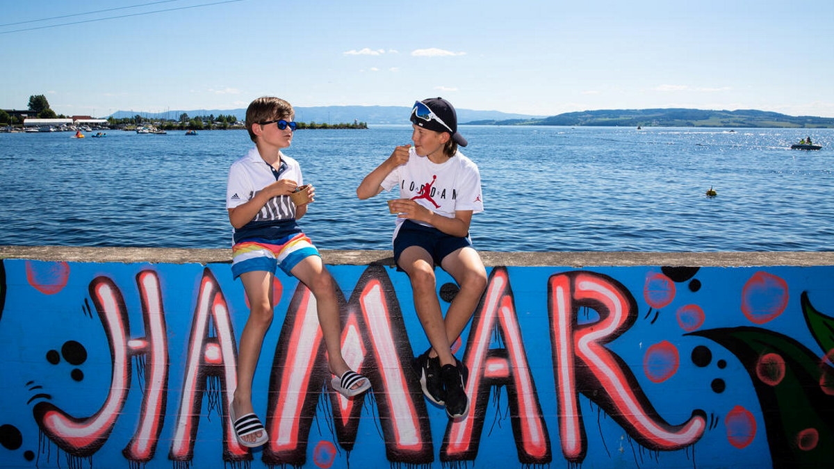 To barn som sitter og spiser is på en grafitti-dekorert mur der det står Hamar