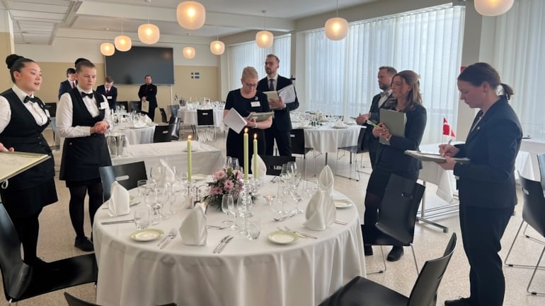En rekke mennesker som står rundt et dekket bord. Foto