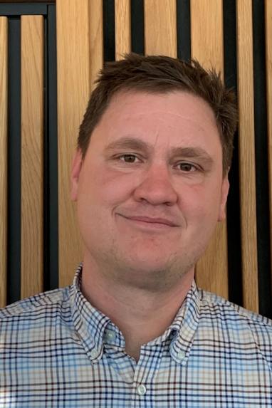 Et portrettbilde av en mann som smiler til kamera.