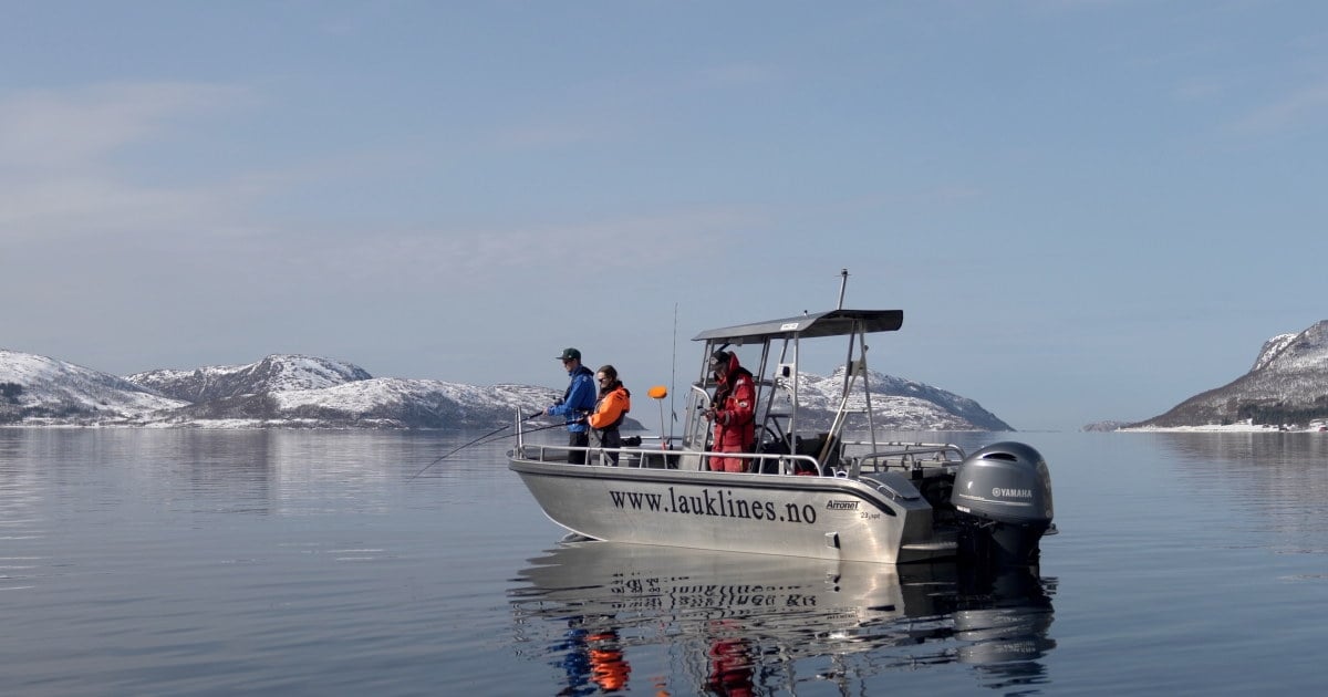 En motorbåt med fiskere om bord, på stille hav. Foto